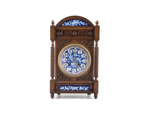 AN ARTS & CRAFTS STAINED OAK CASED MANTLE CLOCK,in the style of Lewis F Day, the arch top with gallery rail above a blue and 