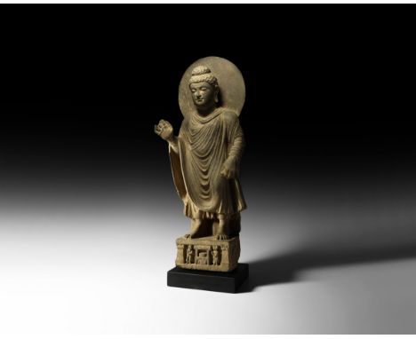 2nd-3rd century AD. A carved schist figure of Buddha standing nimbate with loose sanghati mantle over his tunic, face with se