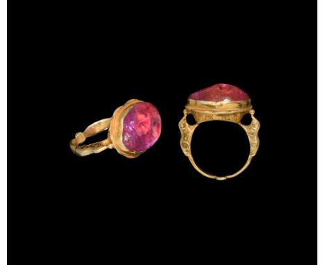 17th century AD. A polished irregular ellipsoid ruby of vibrant rose colour, set in a later gold ring with open underside to 