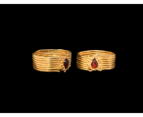 4th century BC. A gold finger ring of parallel hoops with applied piriform cell, granules to the rim and inset garnet cabocho