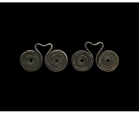 2nd millennium BC. A matched pair of silver pendants, each formed as two coiled ends of a rod with heart-shaped loop between 