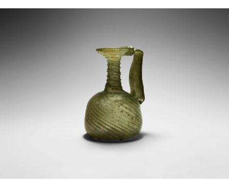 4th century AD. An aqua green glass vessel with iridescent surface, domed body with pontil base and twisted fluting, slender 