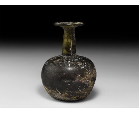 3rd-4th century AD. A glass bottle with dimple base, rounded profile, tapering neck and flared mouth with chamfered rim. Cf. 
