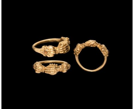 19th century AD. A gold finger ring with clasped-hands motif to the bezel, scroll with inset carnelian cabochon to each shoul