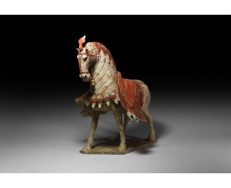 Six Dynasties, 220-589 AD. A ceramic figure of a horse in advancing pose with scarlet and maroon painted detailing, plume to 
