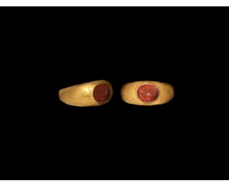 1st-2nd century AD. A carnelian cloison with intaglio dolphin motif, set into a later hollow-formed gold finger ring.  4.48 g