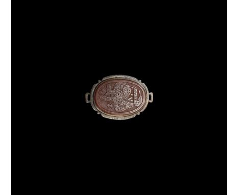 20th century AD. A silver ellipsoid plaque with loop to each end, raised cell, inset carnelian panel with reserved calligraph