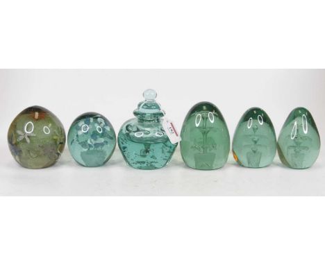 A matched set of three green tinted end of day glass weights each with an urn issuing flowers to the centre, height of larges