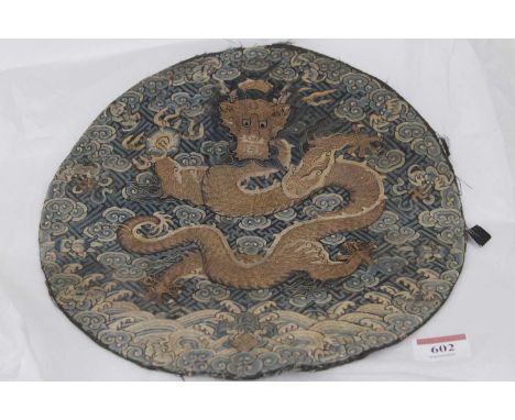 A Chinese silk embroidered badge panel, with a five-claw dragon clutching a pearl in gold thread amongst clouds, dia.26cm