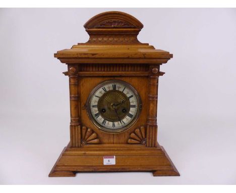 A late Victorian oak cased mantel clock, the brass dial having an enamel chapter ring with Roman numerals, having an eight da