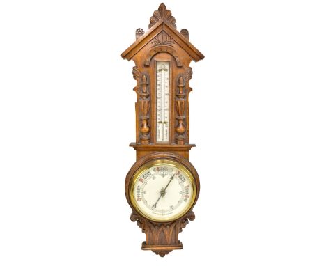 An Edwardian carved oak aneroid barometer with thermometer upper dial, length 88cm.