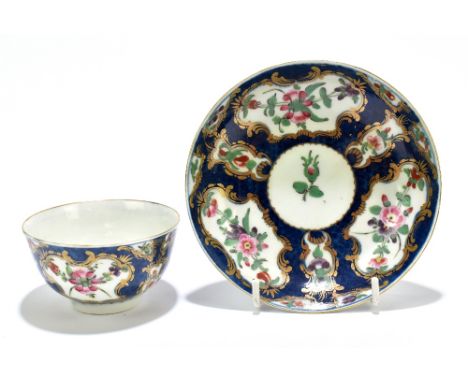 An 18th century Worcester clobbered tea bowl and saucer decorated with floral sprays in gilt-heightened vignettes on a mottle