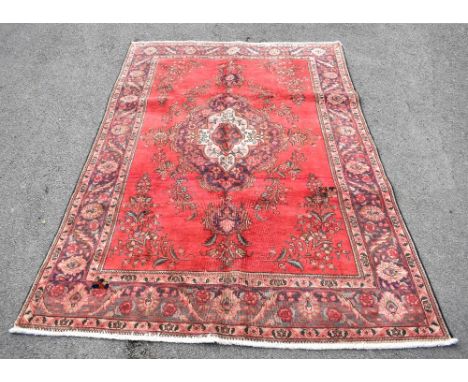 A Persian Tabriz wool carpet, worked with a floral pattern against a red ground, 284cm x 196cmAdditional InformationWorn thro