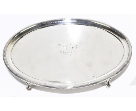 A William IV hallmarked silver teapot stand of oval form, with cast edge, raised on four swept feet, with engraved initials W