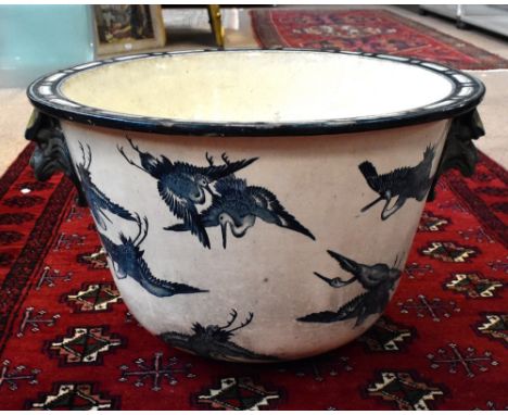 A large late 19th century French ceramic twin handled planter, with mask head handles, decorated with storks to the body, pai