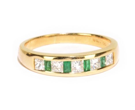 An 18ct yellow gold emerald and diamond ring, the channel set stones featuring five princess cut diamonds, each weighing appr