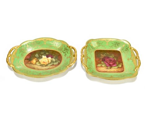F HOWARD FOR COALPORT; two hand painted twin handled bowls, each decorated with roses inside gilt scrolling detail on a green