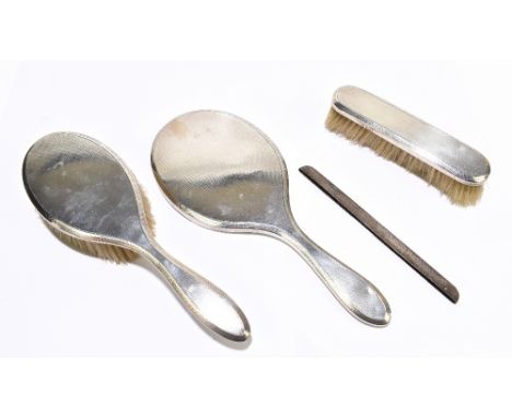 A hallmarked silver three piece dressing table set, with engine turned detailing, London 1904, with a silver comb cover (4)