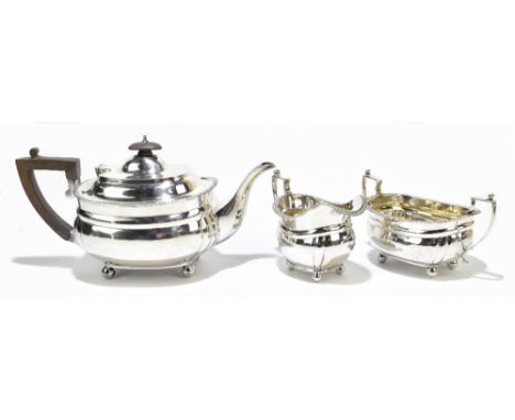 CHARLES STEWART HARRIS; a George V hallmarked silver three piece tea service with cast rim, London 1914, each raised on four 