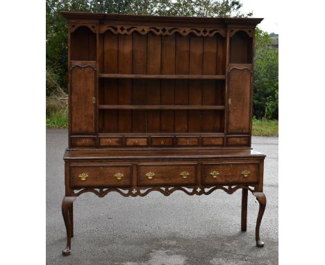 An early 19th century oak and mahogany crossbanded dresser, the invert breakfront moulded cornice above bordered plate rack w