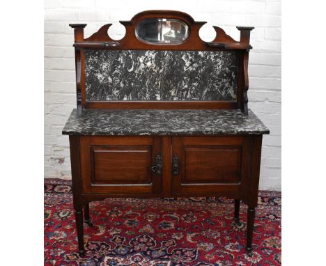 An Edwardian marble top wash stand, the raised back with an oval mirror pane and marble panel, above a marble top and two cup