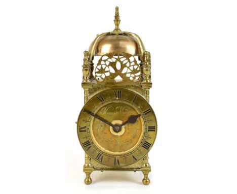 THOMAS MUDGE; an early 20th century brass lantern clock, the applied chapter ring with Roman numerals, raised on four ball fe