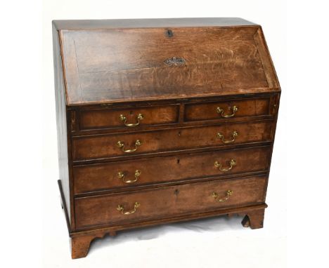A late George III oak and mahogany crossbanded North Country bureau with carved detail to fall front, sectioned interior and 