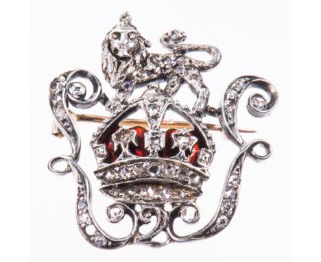 AN ENAMEL AND DIAMOND REGIMENTAL BROOCH, the crown with red enamel detailing within a scroll surround and lion motif, set thr