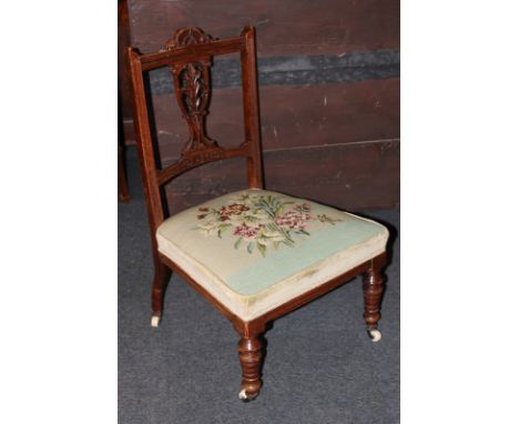 A Victorian low chair with carved pierced back and floral tapestry seat