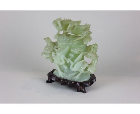 A Chinese green jade coloured glass carved ornamental teapot decorated with storks amongst foliage on hardwood base, 17cm hig