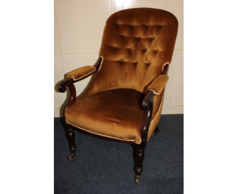 An Edwardian rosewood button back armchair with green velvet upholstery on turned legs and castors