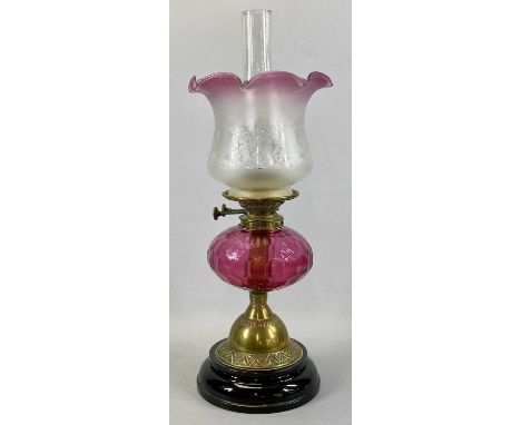 VICTORIAN OIL LAMP, with black ceramic base, embossed brass column, facetted circular cranberry glass reservoir, Duplex twin 
