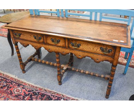 An Oak Three Drawer Dresser Base, in 17th century style, with a shaped and pierced apron over bobbin-turned supports and stre