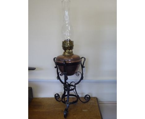 An Antique Copper and Brass Oil Lamp, held within a wrought iron support, approx 66 cms