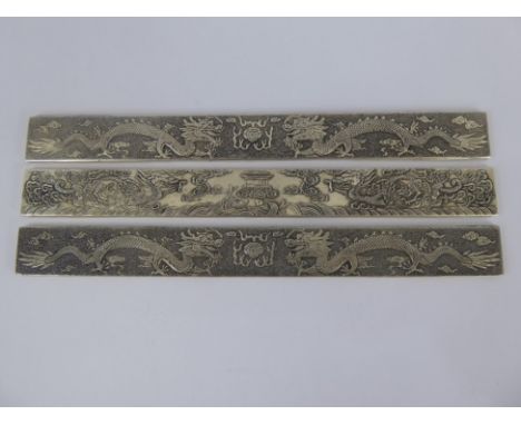 A Pair of Chinese Silver Scroll Weights, character marks 990 silver, depicting chasing dragons amongst cloud scroll together 