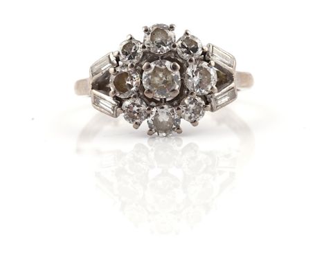 A DIAMOND NINE STONE CLUSTER RINGClaw set with the principal circular cut diamond to the centre, in a surround of eight small