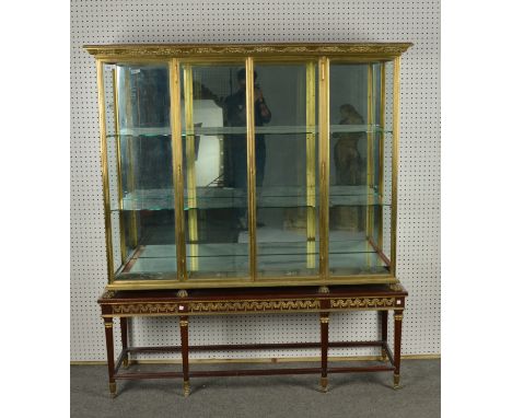 A LACQUERED BRASS MIRROR BACKED DISPLAY CABINET (2)With a pair of central doors on lion’s paw feet mounted  on associated Lou