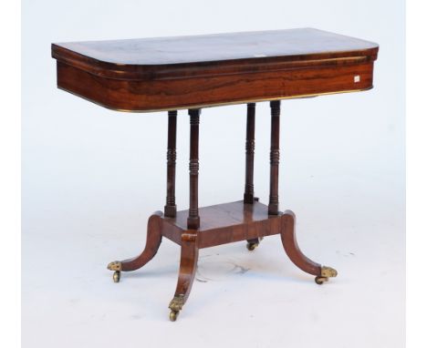 A REGENCY BRASS MOUNTED ROSEWOOD CARD TABLEWith line inlaid and crossbanded fold over top, on four turned and downswept suppo