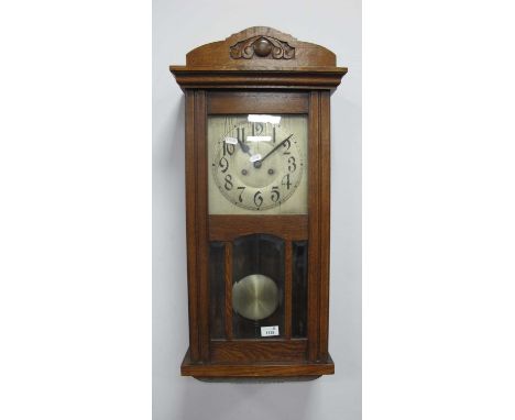 1940s Oak Cased Wall Clock, with a silver dial, Arabic numbers, glazed bevelled door.