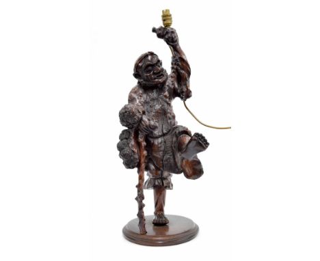 Chinese hardwood carved figure of a peasant with one leg aloft holding a stick, mounted upon a circular base, 27.5" high