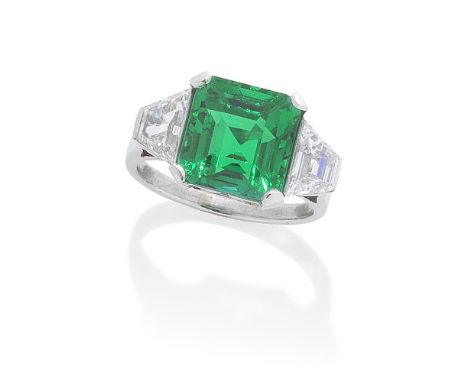 EMERALD AND DIAMOND RINGThe step-cut emerald, weighing 4.47 carats, between trapezoid-cut diamonds, diamonds approximately 1.