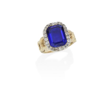 SAPPHIRE AND DIAMOND RINGThe step-cut sapphire, weighing 7.87 carats, within a surround of old brilliant-cut and cushion-shap