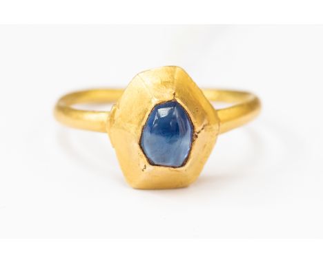 A 13th Century gold ring, with plain band hoop; the raised bezel with segmented sides forming a hexagon set with a cabochon s