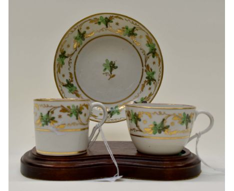 A Pinxton trio, pattern 312, including coffee can, saucer and tea cup, decorated in gold and green, gilt numbers [3]Some wear