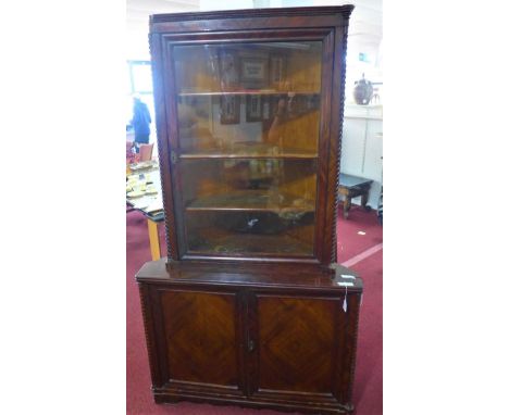 A large mahogany corner bookcase, with glazed door flanked by barley twist columns (one missing Corinthian capital), above tw