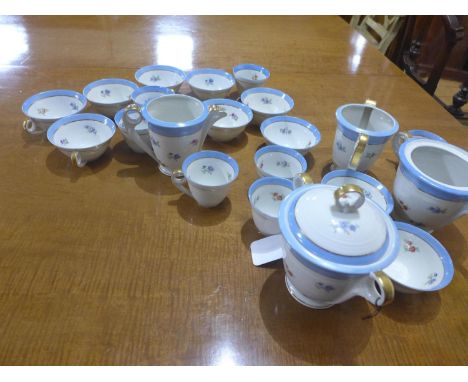 A French porcelain part tea service, decorated with flowers and having blue and gilt rims, to include teacups, milk jugs and 