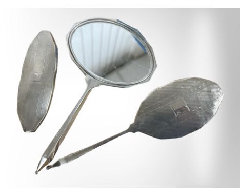 A silver dressing table mirror and two brushes with engine turned decoration, mirror 23.5cm long. 