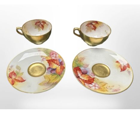 A pair of Royal Worcester porcelain teacups and saucers, hand painted with autumn leaves and blackberries by K Blake, saucers