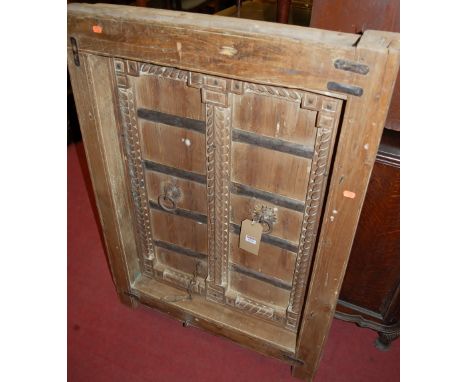 An Indonesian teak and metal bound window frame, enclosing pair of hinged shutters, each with ring handles, 107 x 80cm 