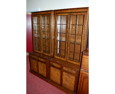A pair of contemporary walnut and burr walnut display cabinets, each having twin glazed upper doors enclosing glass shelves, 